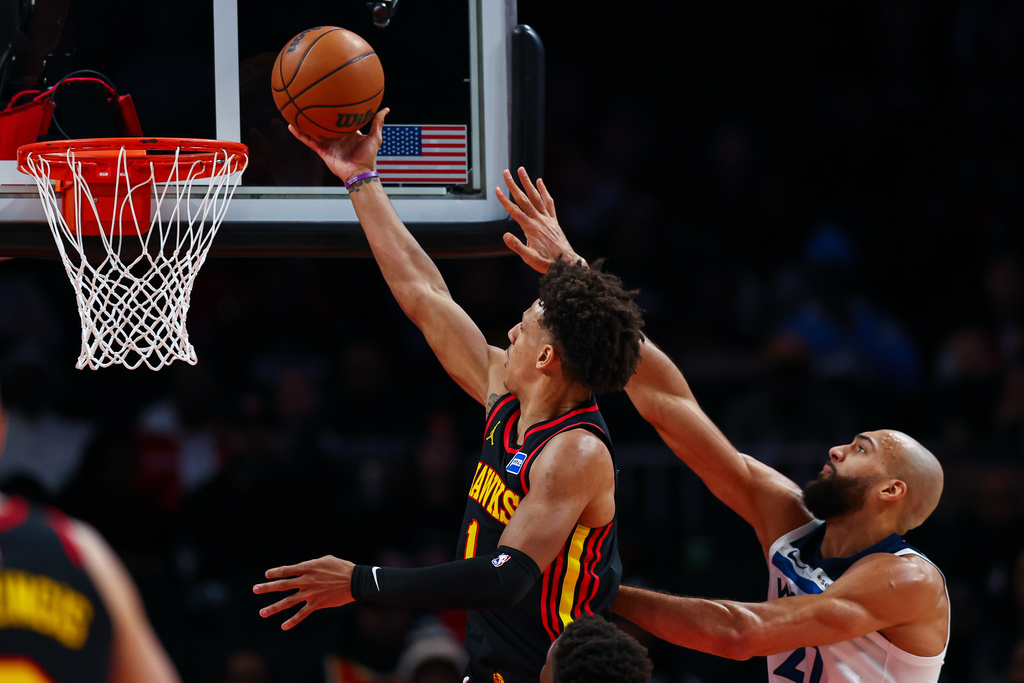 Atlanta Hawks forward Jalen Johnson, left, shoots against Minnesota Timberwolves center Rudy Gobert during the first half of an NBA basketball game, Wednesday, Dec. 31, 2025, in Atlanta. (AP Photo/Colin Hubbard)