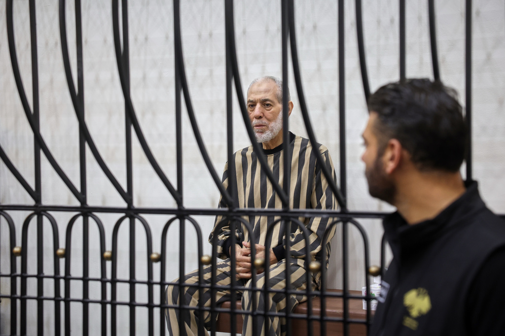 Syria's former grand mufti under ousted President Bashar Assad, Ahmad Badreddine Hassoun, sits in the defendants' cage before a court sentences him to life in prison at the Palace of Justice in Damascus, Syria, Monday, Aug. 24, 2026. (AP Photo/Ghaith Alsayed)
