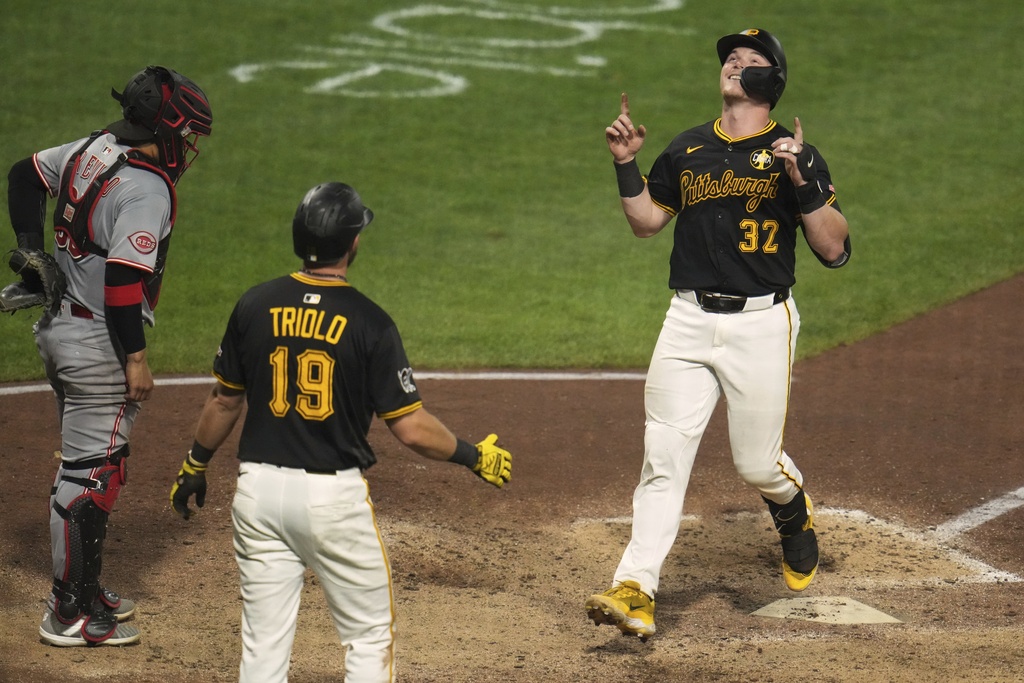 Pittsburgh Pirates' Henry Davis (32) is greeted by Jared Triolo (19) as he crosses home plate after they scored on his two-run home run off Cincinnati Reds pitcher Brent Suter during the seventh inning of a baseball game in Pittsburgh, Thursday, Aug. 7, 2025. (AP Photo/Gene J. Puskar)