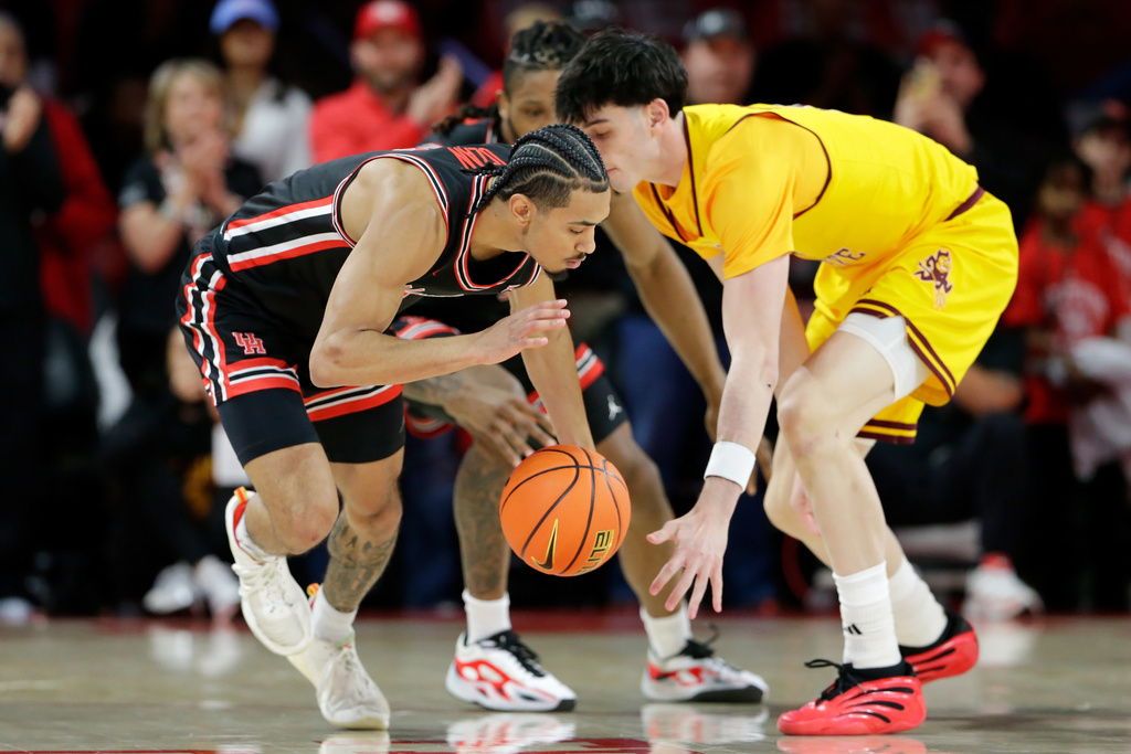Houston guard Milos Uzan, left, gets a turnover after knocking away the ball from Arizona State forward Santiago Trouet, right, during the first half of an NCAA college basketball game Sunday, Jan. 18, 2026, in Houston. (AP Photo/Michael Wyke)