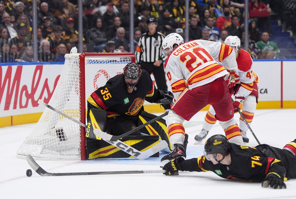 Vancouver Canucks goalie Thatcher Demko (35) watches as teammate Jake DeBrusk (74) swats the puck away from Calgary Flames' Blake Coleman (20) during the second period of an NHL hockey game in Vancouver, British Columbia, Thursday, Oct. 9, 2025. (Darryl Dyck/The Canadian Press via AP)
