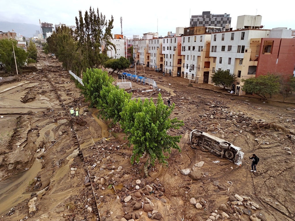 A man takes photos on a destroyed road after heavy rain triggered flooding in Arequipa, Peru, Monday, Feb. 23, 2026. (AP Photo/Jose Sotomayor)