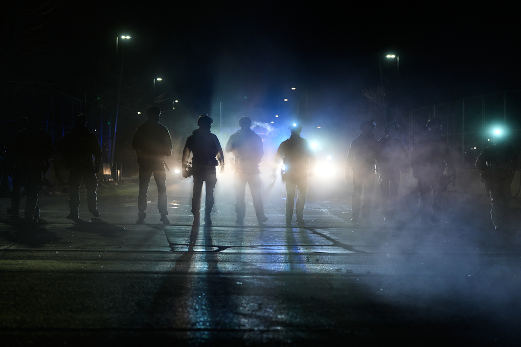 Federal immigration officers are seen outside Bishop Whipple Federal Building after tear gas was deployed Monday, Jan. 12, 2026, in Minneapolis. (AP Photo/Jen Golbeck)