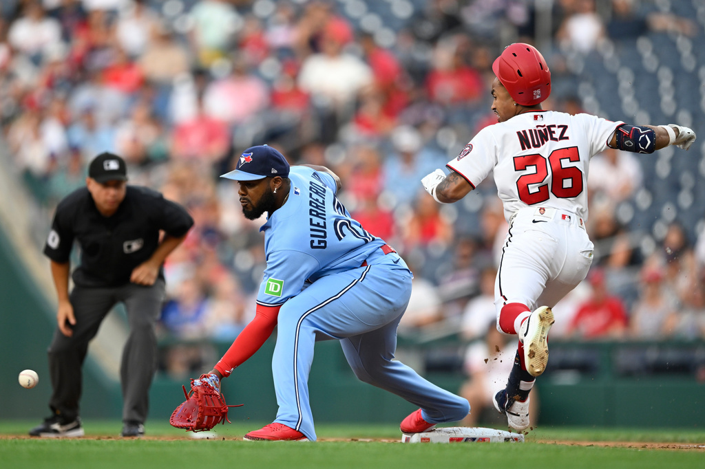Washington Nationals' Nasim Nuñez (26) beats out a throw to Toronto Blue Jays first baseman Vladimir Guerrero Jr., center, during the second inning of a baseball game, Monday, July 27, 2026, in Washington. (AP Photo/John McDonnell)