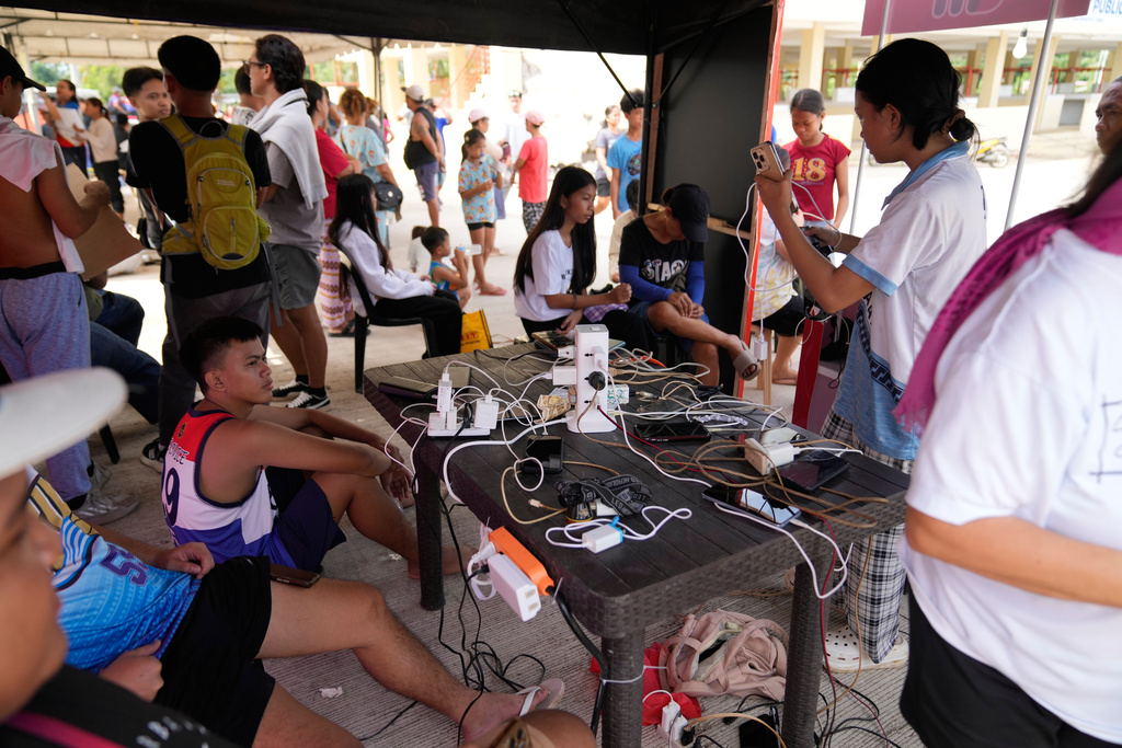 Survivors of Tuesday's earthquake charge their phones on Thursday, Oct. 2, 2025 in San Remigio, Cebu Province, Central Philippines. (AP Photo/Aaron Favila)