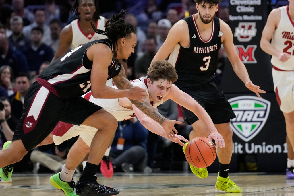 Miami (Ohio) guard Peter Suder, center, dives for the ball next to Massachusetts guard Marcus Banks, left, in the second half of a basketball game in the quarterfinals of the Mid-American Conference tournament, Thursday, March 12, 2026, in Cleveland. (AP Photo/Sue Ogrocki)