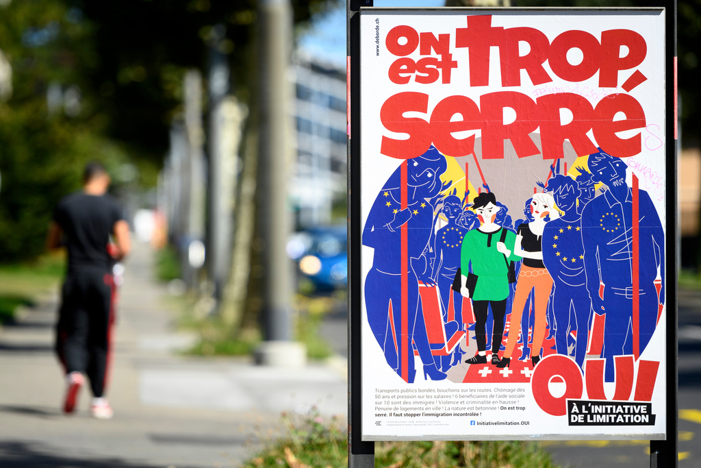 FILE - A poster of the Swiss People's Party (SVP) for a moderate immigration initiative reading 'we're too tight!' is displayed in a street in Lausanne, Switzerland, Sept. 8, 2020. (Laurent Gillieron/Keystone via AP, File)