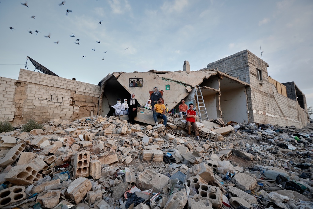 A group of Syrian graffiti artists pose for a photo after painting a mural on the collapsed ceiling of a war-damaged house in Daraya, on the outskirts of Damascus, Syria, Monday, Nov. 3, 2025. (AP Photo/Omar Sanadiki)
