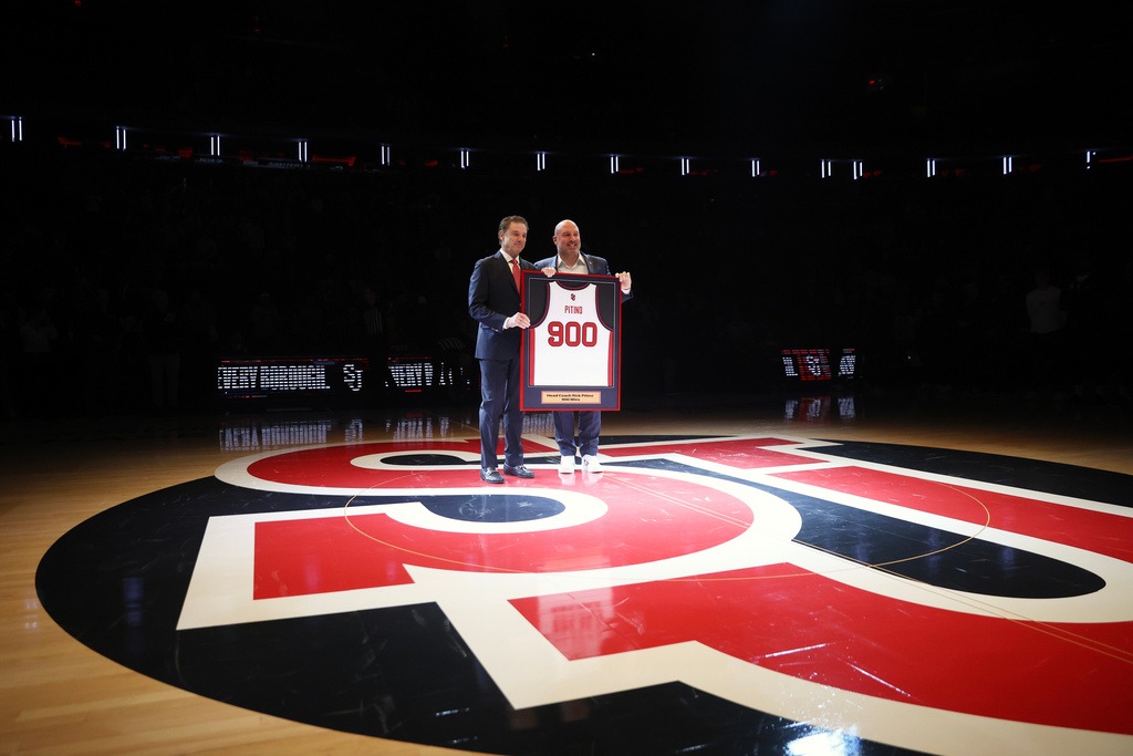 St. John's head coach Rick Pitino, left, is presented with a jersey by Ed Kull for his 900th win before an NCAA college basketball game against Butler, Wednesday, Jan. 28, 2026, in New York. (AP Photo/Heather Khalifa)