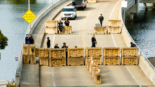 Coast Guardsmen stand watch behind a barrier at Coast Guard Base Alameda on Friday, Oct. 24, 2025, in Oakland, Calif. The barrier was erected earlier in the day after law enforcement officers fired on a vehicle as it backed towards them. (AP Photo/Noah Berger) Coast Guardsmen stand watch behind a barrier at Coast Guard Base Alameda on Friday, Oct. 24, 2025, in Oakland, Calif. The barrier was erected earlier in the day after law enforcement officers fired on a vehicle as it backed towards them. (AP Photo/Noah Berger)