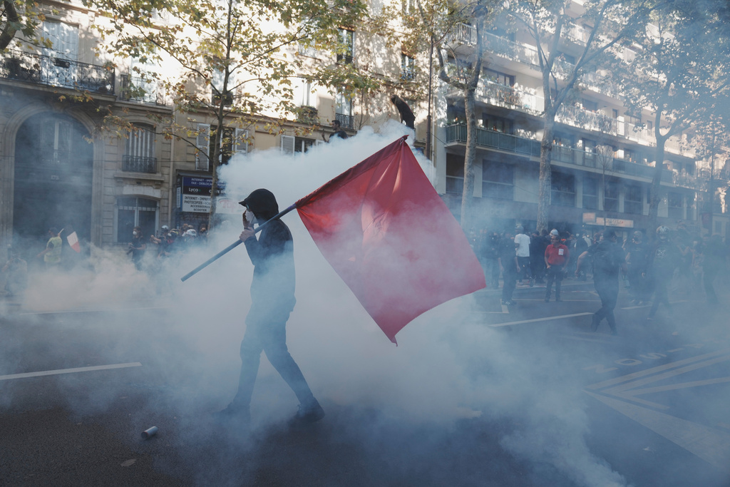 Protesters march in the teargas during a demonstration called by major trade unions to oppose budget cuts, in Paris, France, Thursday, Sept. 18, 2025. (AP Photo/Thibault Camus)