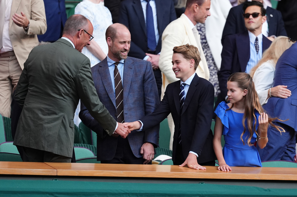 From left, German Chancellor Friedrich Merz, left, greets Britain's Prince William, Prince George and Princess Charlotte during the men's singles final between Jannik Sinner of Italy and Alexander Zverev of Germany at the Wimbledon Tennis Championships in London, England, Sunday, July 12, 2026. (Mike Egerton/PA via AP)