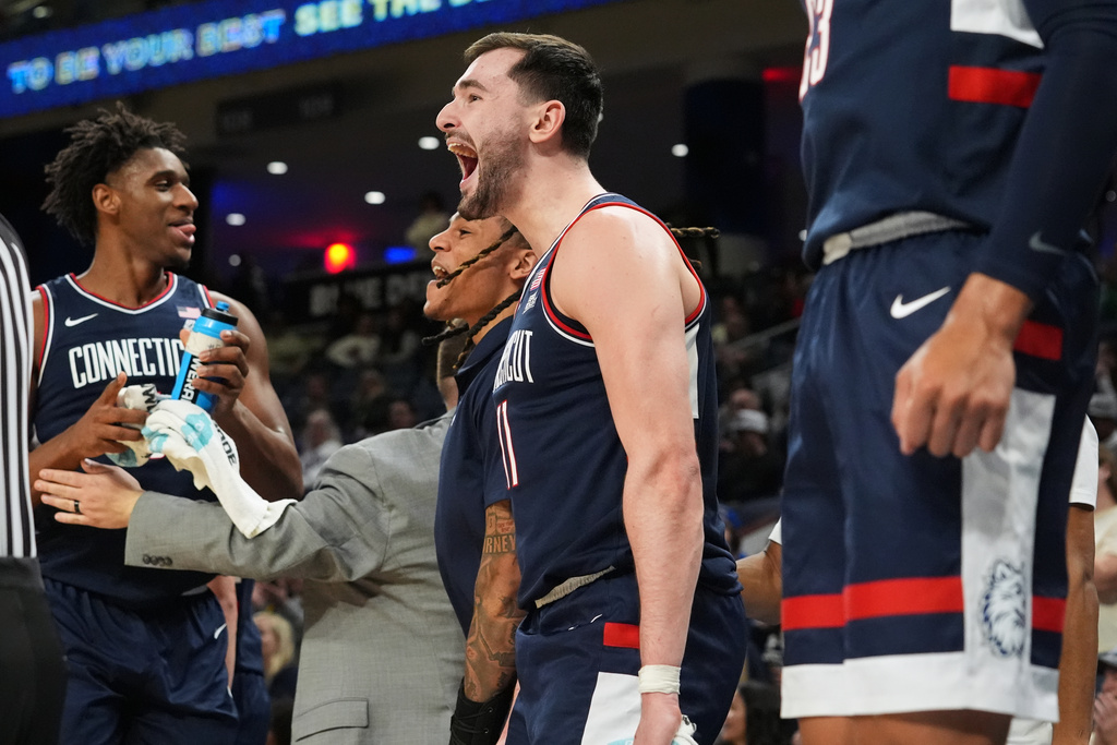UConn forward Alex Karaban, center right, and guard Solo Ball, center left, celebrate after guard Alec Millender (not shown) scored during the second half of an NCAA college basketball game against DePaul in Chicago, Sunday, Dec. 21, 2025. (AP Photo/Nam Y. Huh)