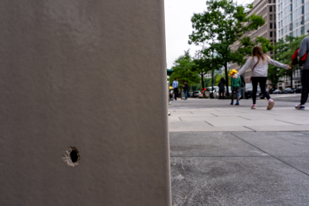 People walk past a hole in the wall of a building near the scene of a shooting close to the White House, Sunday, May 24, 2026, in Washington. (AP Photo/Alex Brandon)