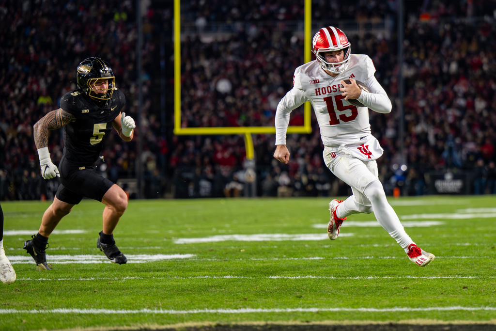 Indiana quarterback Fernando Mendoza (15) runs toward the end zone to score while being pursued by Purdue linebacker Charles Correa (5) during the first half of an NCAA college football game, Friday, Nov. 28, 2025, in West Lafayette, Ind. (AP Photo/Doug McSchooler)