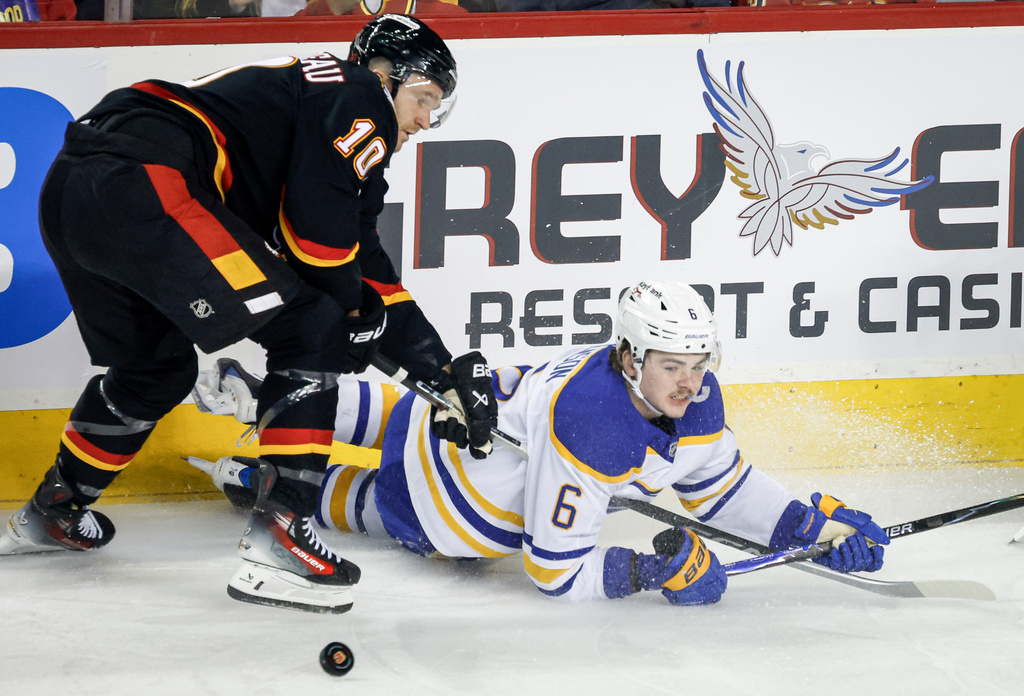 Buffalo Sabres' Zach Benson, right, is checked by Calgary Flames' Jonathan Huberdeau during the first period of an NHL hockey game in Calgary, Alberta, Monday, Dec. 8, 2025. (Jeff McIntosh/The Canadian Press via AP)