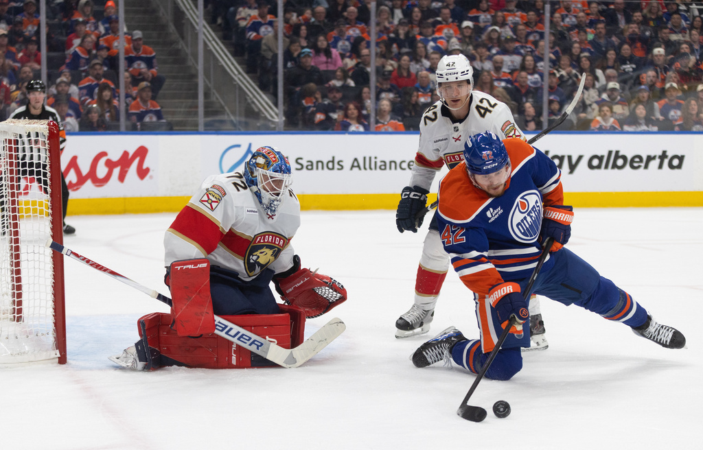 Florida Panthers goalie Sergei Bobrovsky (72) makes a save as teammate Gustav Forsling (42) and Edmonton Oilers' Kasperi Kapanen (42) battle for the rebound during second-period NHL hockey game action in Edmonton, Alberta, Thursday March 19, 2026.(Jason Franson/The Canadian Press via AP)