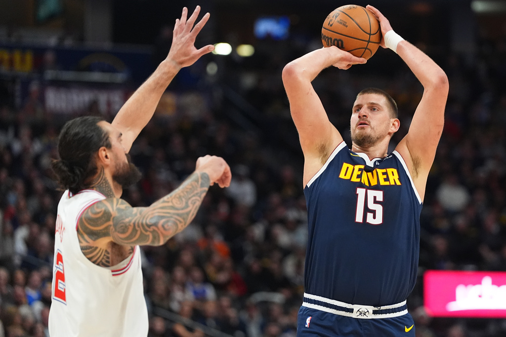 Denver Nuggets center Nikola Jokić, right, looks to shoot a basket over Houston Rockets center Steven Adams, left, in the first half of an NBA basketball game Monday, Dec. 15, 2025, in Denver. (AP Photo/David Zalubowski)