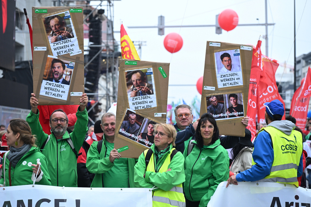Demonstrators hold signs with photos of Belgian politicians which reads 'keep quiet, work and pay', during a general strike in Brussels, Tuesday, Oct. 14, 2025. (AP Photo/Harry Nakos)