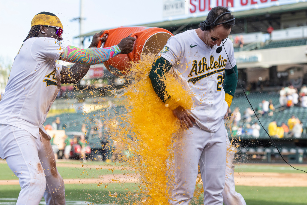 Athletics' Lawrence Butler, left, and Max Muncy dump Gatorade on Brent Rooker, right, after he hit a walk-off three-run home run during the tenth inning of a baseball game against the Houston Astros Sunday, April 5, 2026, in West Sacramento, Calif. (AP Photo/Sara Nevis)