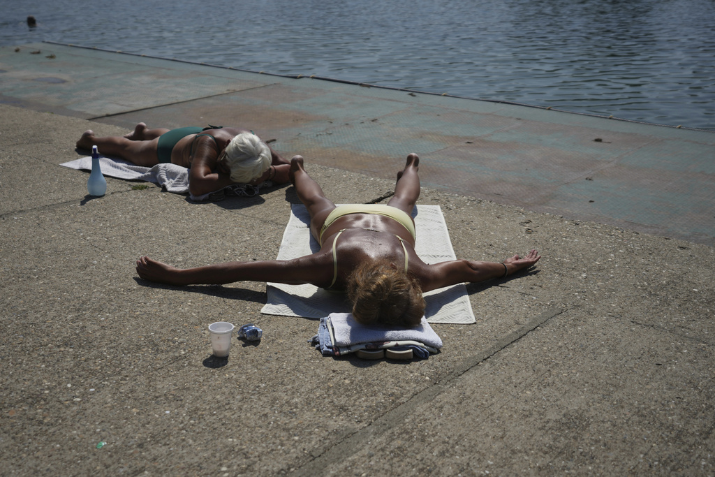 People sunbathe next to the Ada Ciganlija Lake in Belgrade, Serbia, Tuesday, Aug. 12, 2025. (AP Photo/Darko Vojinovic)