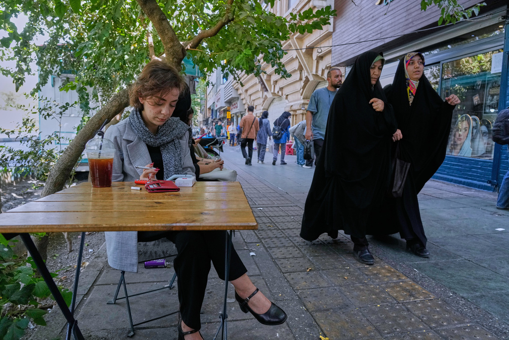 A woman sits in the al fresco dining area of a cafe at the Enqelab-e-Eslami (Islamic Revolution) street, in Tehran, Iran, Saturday, Sept. 27, 2025. (AP Photo/Vahid Salemi)