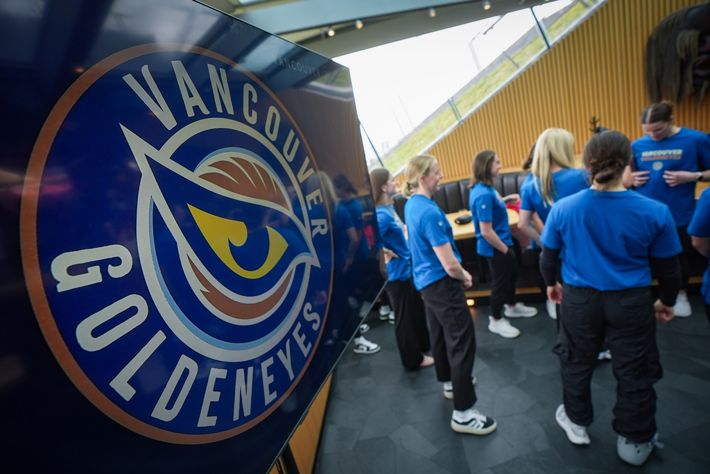 Vancouver Goldeneyes players stand near a display showing their new logo and team name following an unveiling at a PWHL hockey news conference, Thursday, Nov. 6, 2025, in Vancouver, British Columbia. (Darryl Dyck/The Canadian Press via AP)