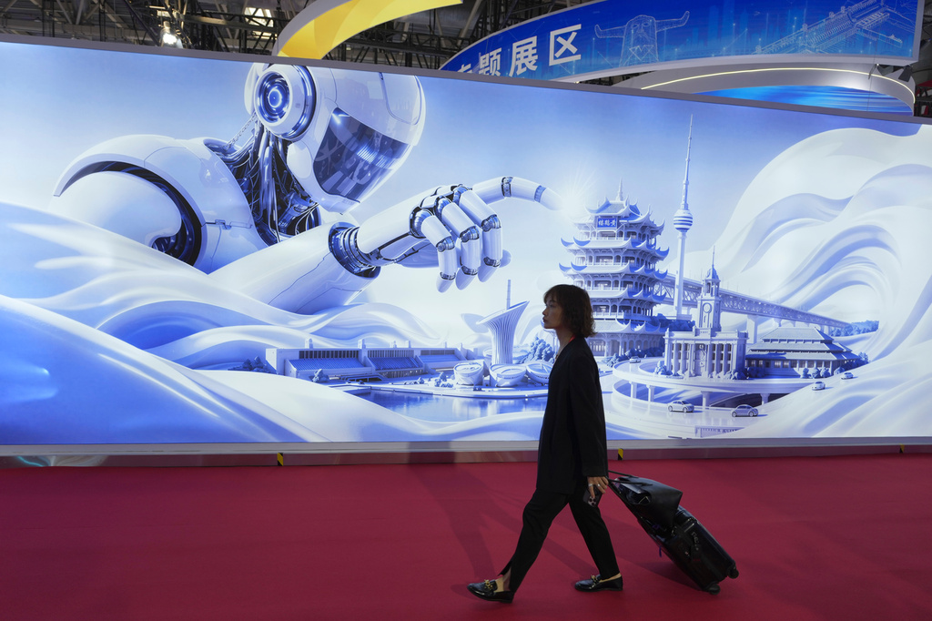 A woman passes a mural depicting a humanoid robot towering over iconic landmarks at the China International Supply Chain Expo in Beijing on Monday, June 22, 2026. (AP Photo/Ng Han Guan)