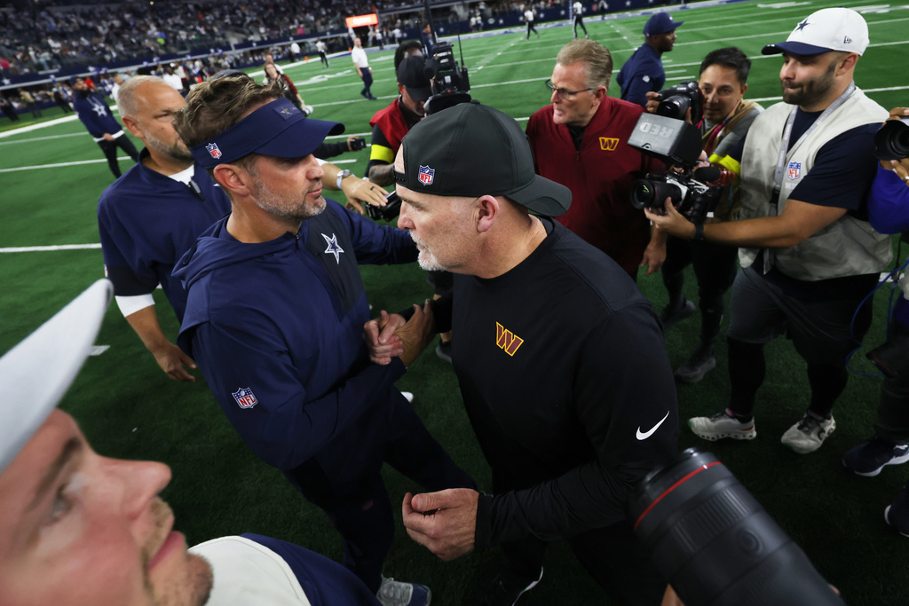 Dallas Cowboys head coach Brian Schottenheimer, left, and Washington Commanders head coach Dan Quinn talk following an NFL football game Sunday, Oct. 19, 2025, in Arlington, Texas. (AP Photo/Gareth Patterson)