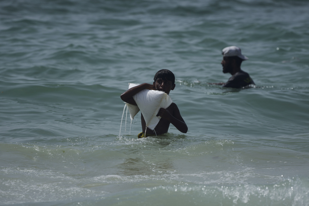 A Palestinian youth carries a sack of aid that landed in the Mediterranean Sea after being airdropped over central Gaza, at the shore of Zawaida, Gaza Strip, July 29, 2025. (AP Photo/Abdel Kareem Hana)
