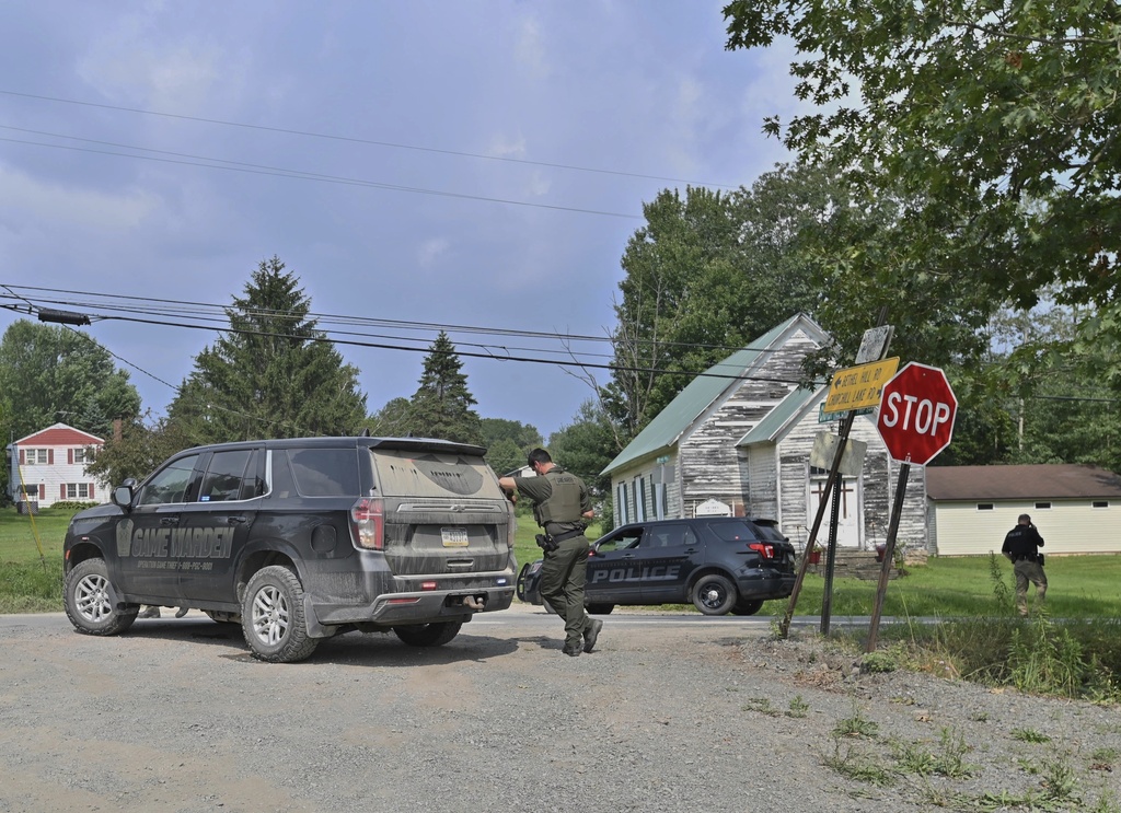 Police officers block the street leading to where two Pennsylvania state troopers were ambushed and shot Thursday, Aug. 7, 2025, near the village of Thompson in Susquehanna County, Pa. (AP Photo/Aimee Dilger)