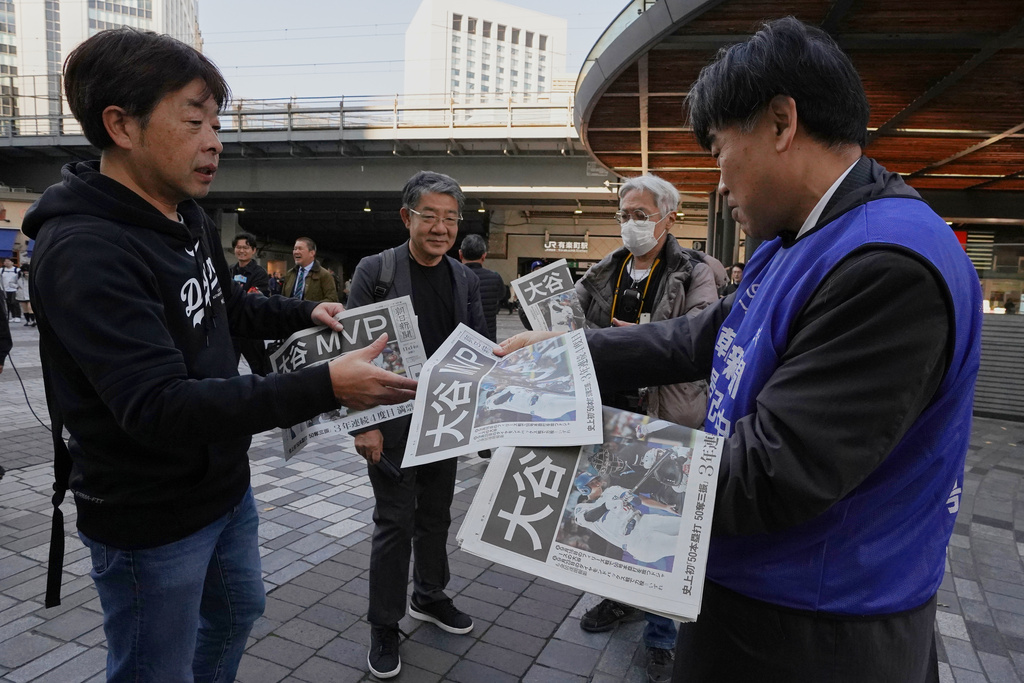 Staff of Japan's newspaper The Asahi Shimbun hands over to passersby, a copy of the extra issue published after the Los Angeles Dodgers Shohei Ohtani won a Most Valuable Player award, in Tokyo, Friday, Nov. 14, 2025. (AP Photo/Koji Ueda)