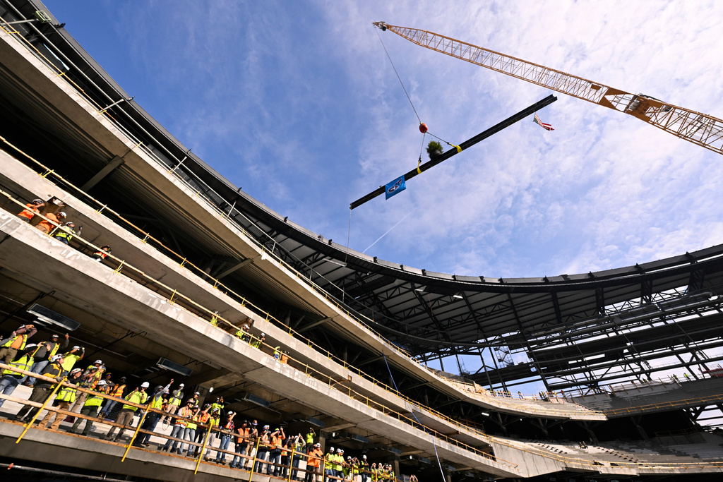 A steel beam is raised to be put in place as construction workers cheer during a topping out ceremony to celebrate the ongoing construction of the Tennessee Titans NFL football new stadium, Friday, Nov. 21, 2025, in Nashville, Tenn. (AP Photo/John Amis)