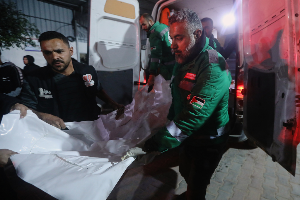 Palestinians carry the body of a person killed in an Israeli military strike as they arrive at Shifa Hospital in Gaza City, Friday, Dec. 19, 2025. (AP Photo/Yousef Al Zanoun)
