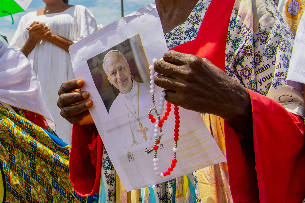A Catholic faithful holds an image of Pope Leo XIV as she waits for his arrival at Yaounde Nsimalen International Airport in Yaounde, Cameroon, Wednesday, April 15, 2026. (AP Photo/Welba Yamo Pascal)