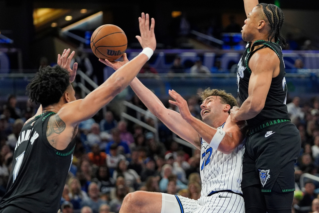 Orlando Magic forward Franz Wagner, center, shoots as he gets caught between Minnesota Timberwolves guard Terrence Shannon Jr., left, and guard Jaylen Clark during the second half of an NBA basketball game, Wednesday, April 8, 2026, in Orlando, Fla. (AP Photo/John Raoux)