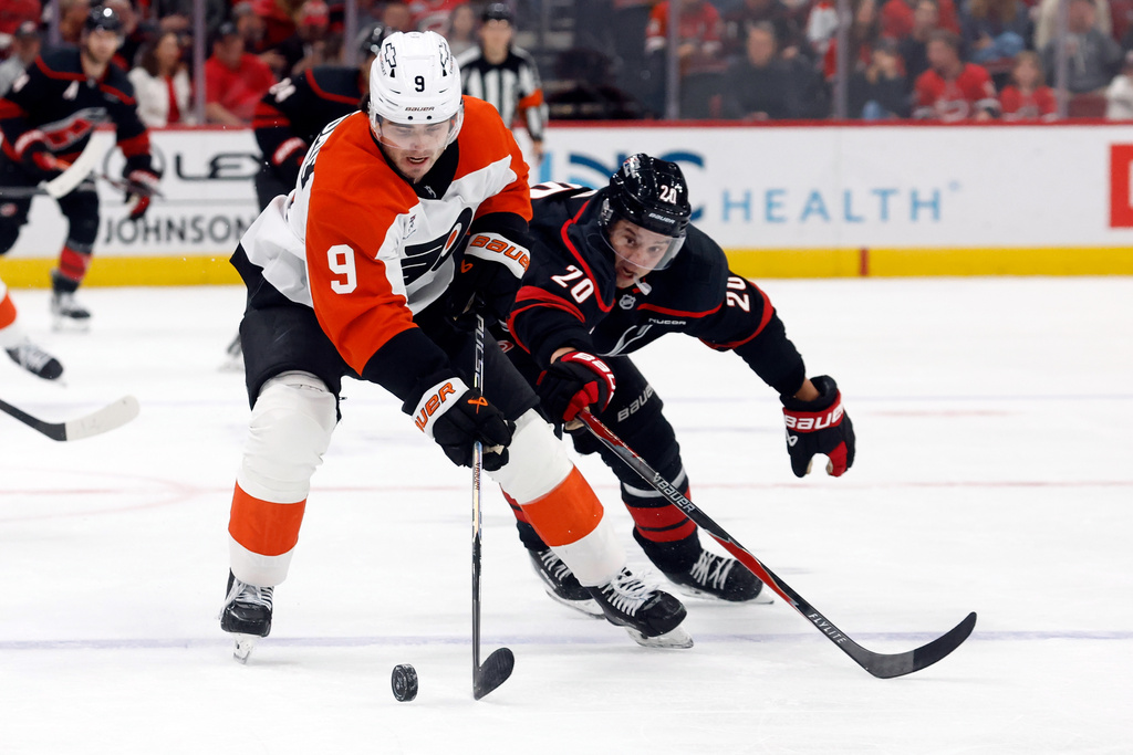 Philadelphia Flyers' Jamie Drysdale (9) protects the puck from Carolina Hurricanes' Sebastian Aho (20) during the second period of an NHL hockey game in Raleigh, N.C., Saturday, Oct. 11, 2025. (AP Photo/Karl DeBlaker)
