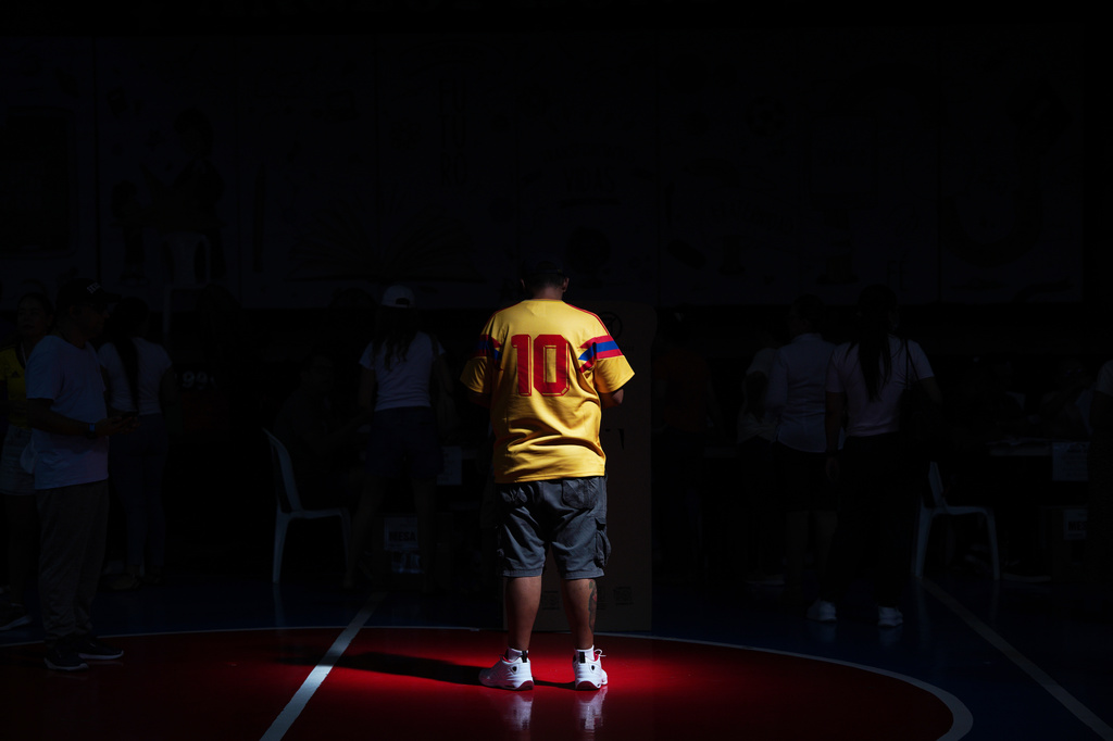 A voter wearing a national soccer team jersey waits for his turn to cast his ballot during the runoff election in Barranquilla, Colombia, Sunday, June 21, 2026. (AP Photo/Ivan Valencia)