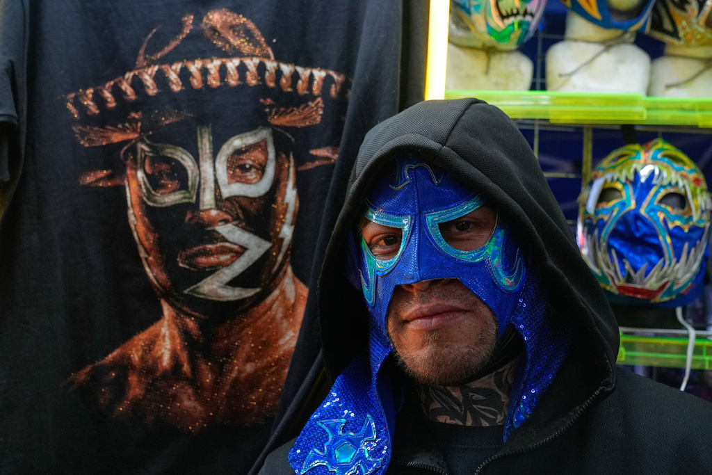 A vendor wears one of his Lucha Libre wrestling masks for sale outside Arena Mexico where performances take place in Mexico City, Friday, Feb. 6, 2026. (AP Photo/Marco Ugarte)