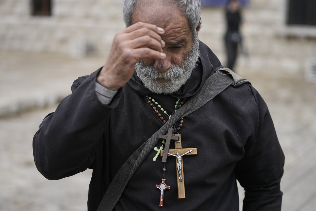A worshipper makes the sign of the cross while wearing several crucifixes around his neck at the shrine of St. Charbel in the northern village of Annaya, Lebanon, Saturday, Nov. 15, 2025. (AP Photo/Hassan Ammar)