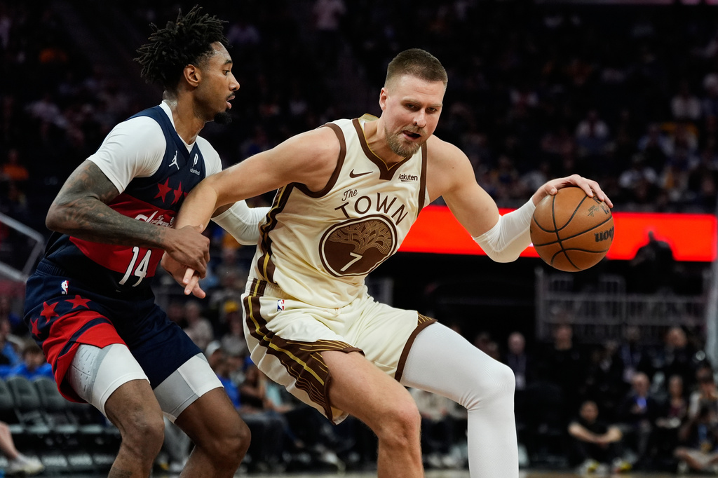 Golden State Warriors center Kristaps Porzingis (7) moves the ball while defended by Washington Wizards forward Leaky Black (14) during the second half of an NBA basketball game, Friday, March 27, 2026, in San Francisco. (AP Photo/Godofredo A. Vásquez)