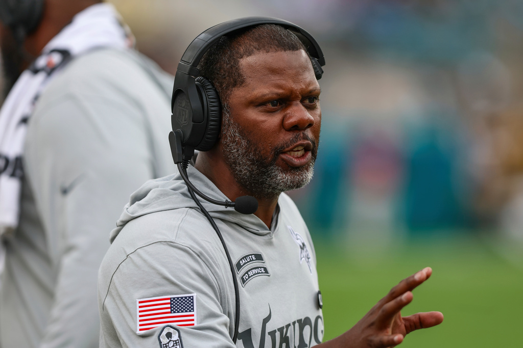 FILE - Minnesota Vikings passing game coordinator/defensive backs coach Daronte Jones speaks with a player while wearing a "Salute to Service" shirt during an NFL football game against the Jacksonville Jaguars, Nov. 10, 2024, in Jacksonville, Fla. (AP Photo/Gary McCullough, File)