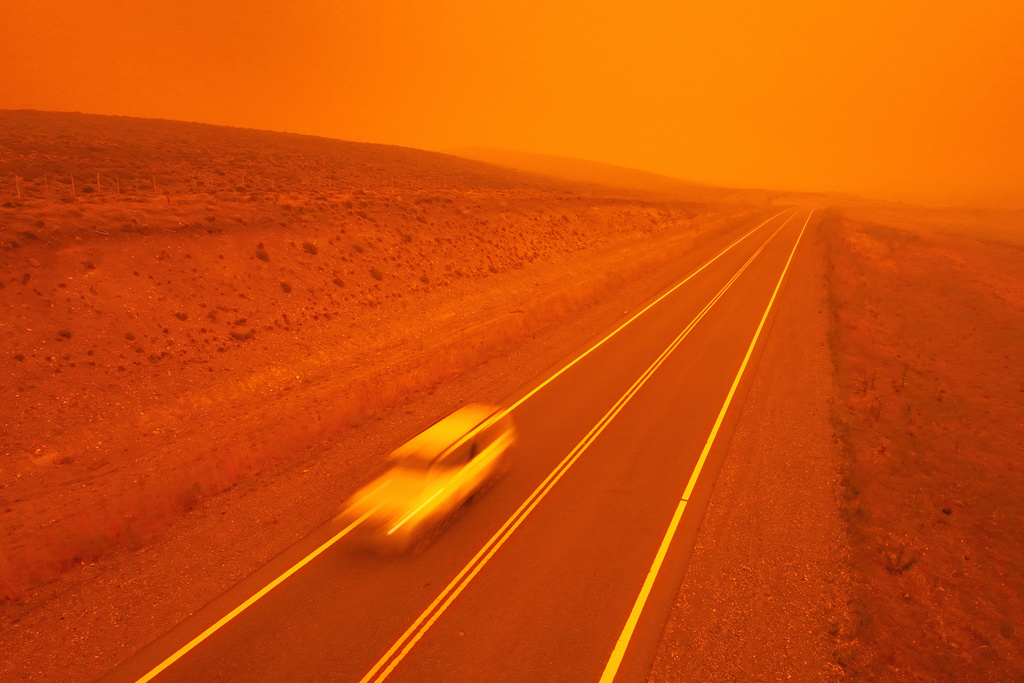 FILE - A car speeds along a road as smoke from wildfires turns the sky red near Cholila, Argentina, Feb. 1, 2026. (AP Photo/Victor R. Caivano, File)
