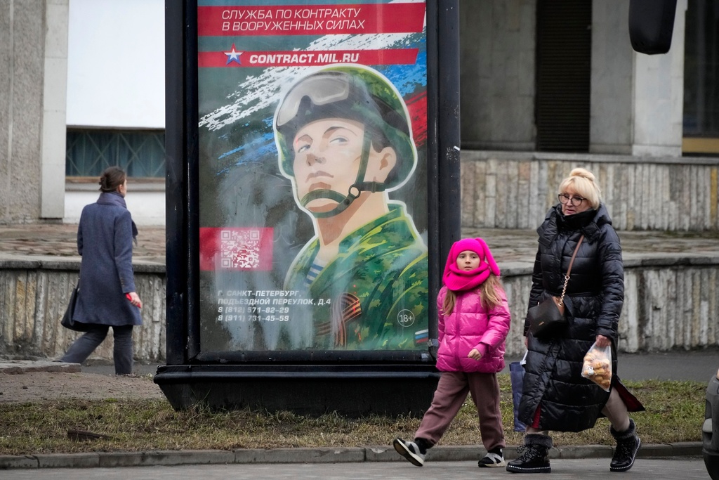 FILE - People walk past an army recruiting billboard with the words "Military service under contract in the armed forces," in St. Petersburg, Russia, March 24, 2023. (AP Photo, File)