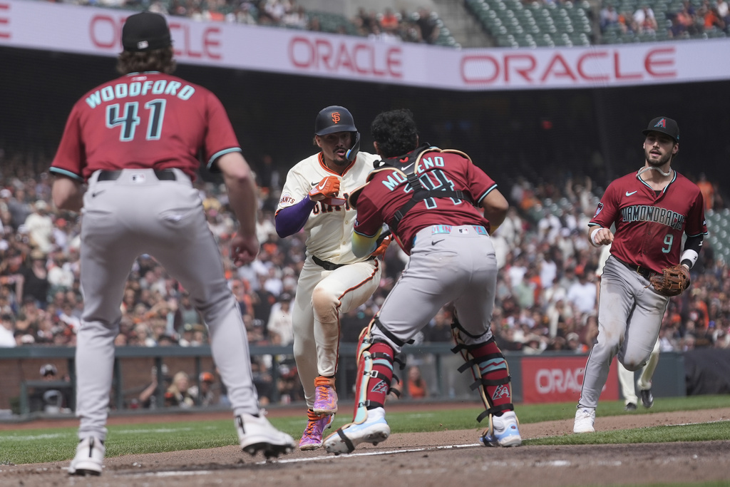 San Francisco Giants' Willy Adames, middle left, is caught in a run down before being tagged out by Arizona Diamondbacks catcher Gabriel Moreno, middle right, during the seventh inning of a baseball game in San Francisco, Wednesday, Sept. 10, 2025. (AP Photo/Jeff Chiu)