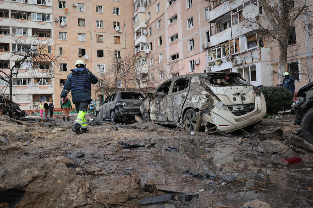 People pass by damaged cars near an apartment building after a Russian attack in Zaporizhzhia, Ukraine, Wednesday, Jan. 28, 2026. (AP Photo/Kateryna Klochko)