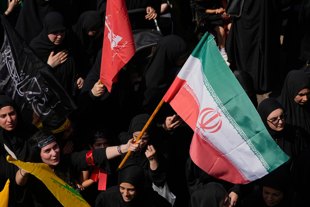 A Hezbollah supporter waves an Iranian flag, as she marches during the holy day of Ashoura that commemorates the 7th century martyrdom of the Prophet Muhammad's grandson Hussein, in Dahiyeh, Beirut's southern suburbs, Lebanon, Friday, June 26, 2026. (AP Photo/Hussein Malla)
