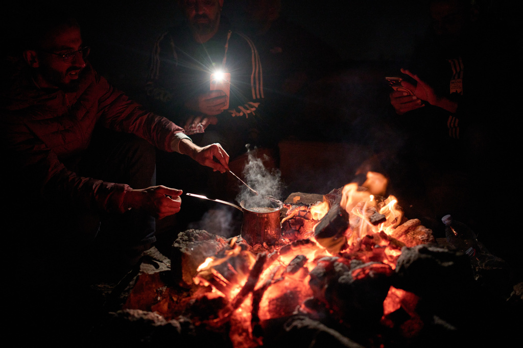 Palestinians prepare coffee as they gather around a bonfire during a volunteer night watch to help prevent Israeli settler attacks in the West Bank town of Sinjil, Tuesday, July 28, 2026. Nightly watches have become a part of daily life, with no government or security force willing to protect them. (AP Photo/Leo Correa)