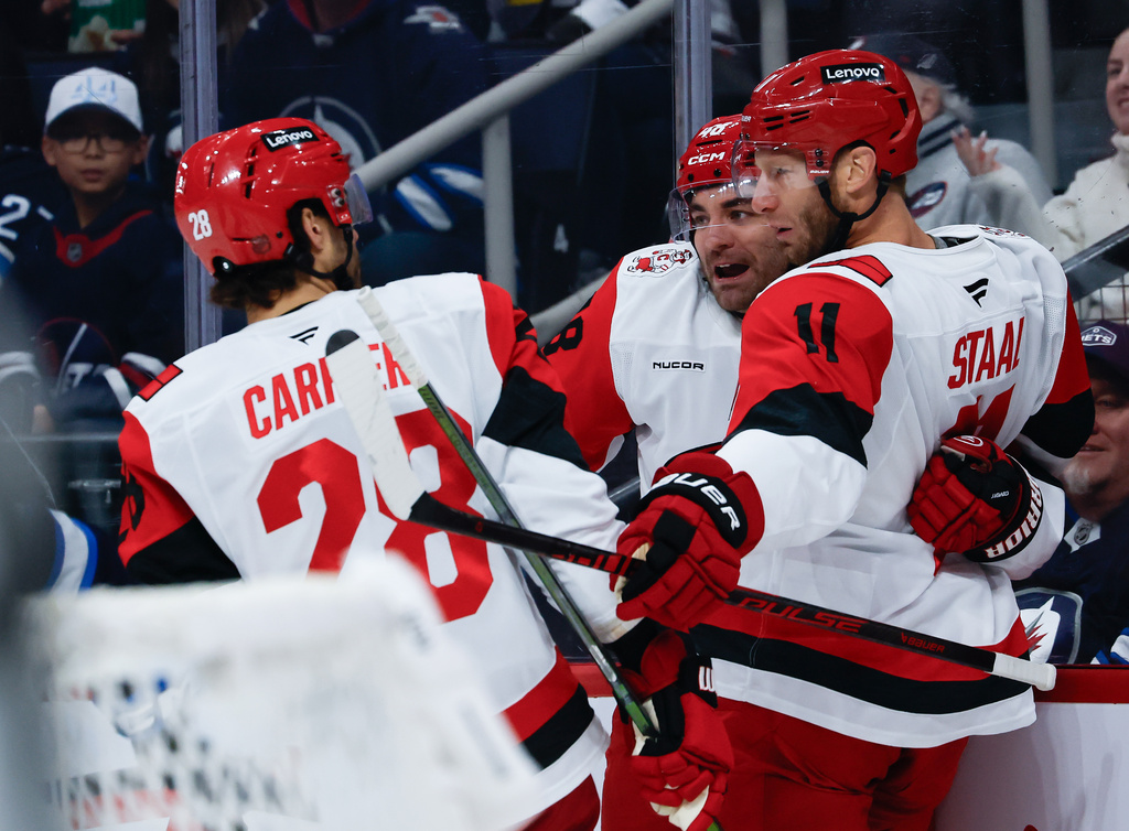 Carolina Hurricanes' William Carrier (28), Jordan Staal (11) and Jordan Martinook (48) celebrate after Staal's goal against the Winnipeg Jets during first-period NHL hockey game action in Winnipeg, Manitoba, Friday, Nov. 21, 2025. (John Woods/The Canadian Press via AP)