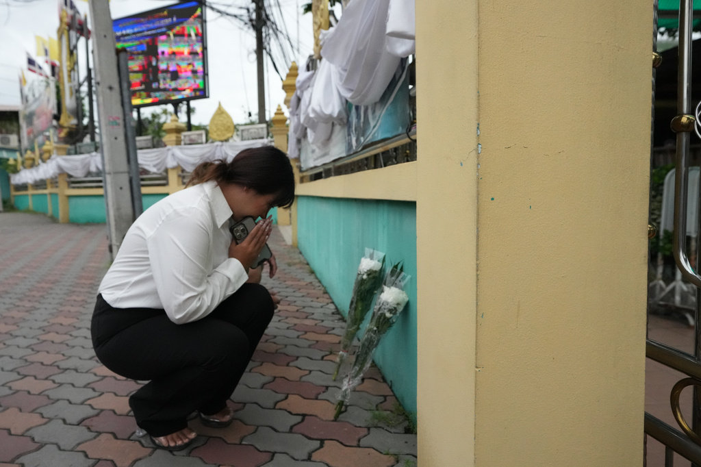 A woman lays flowers and offers prayers at Debsirin Nonthaburi School, a day after the shooting at the school in Nonthaburi province, Thailand, on Saturday, Aug. 8, 2026. (AP Photo/Sakchai Lalit)